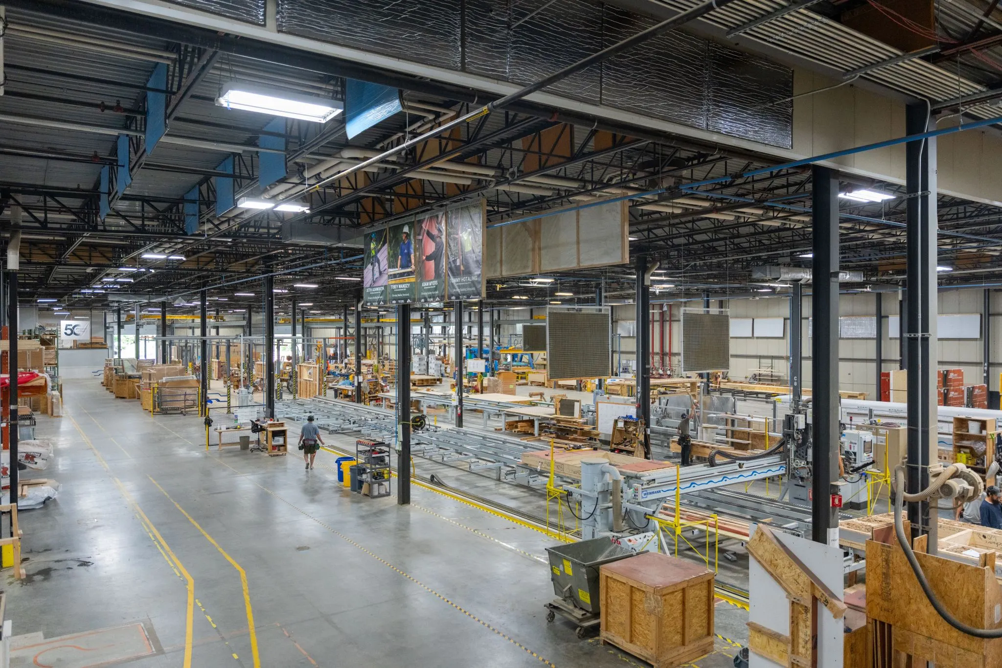Large homebuilding factory floor with production lines and workers.