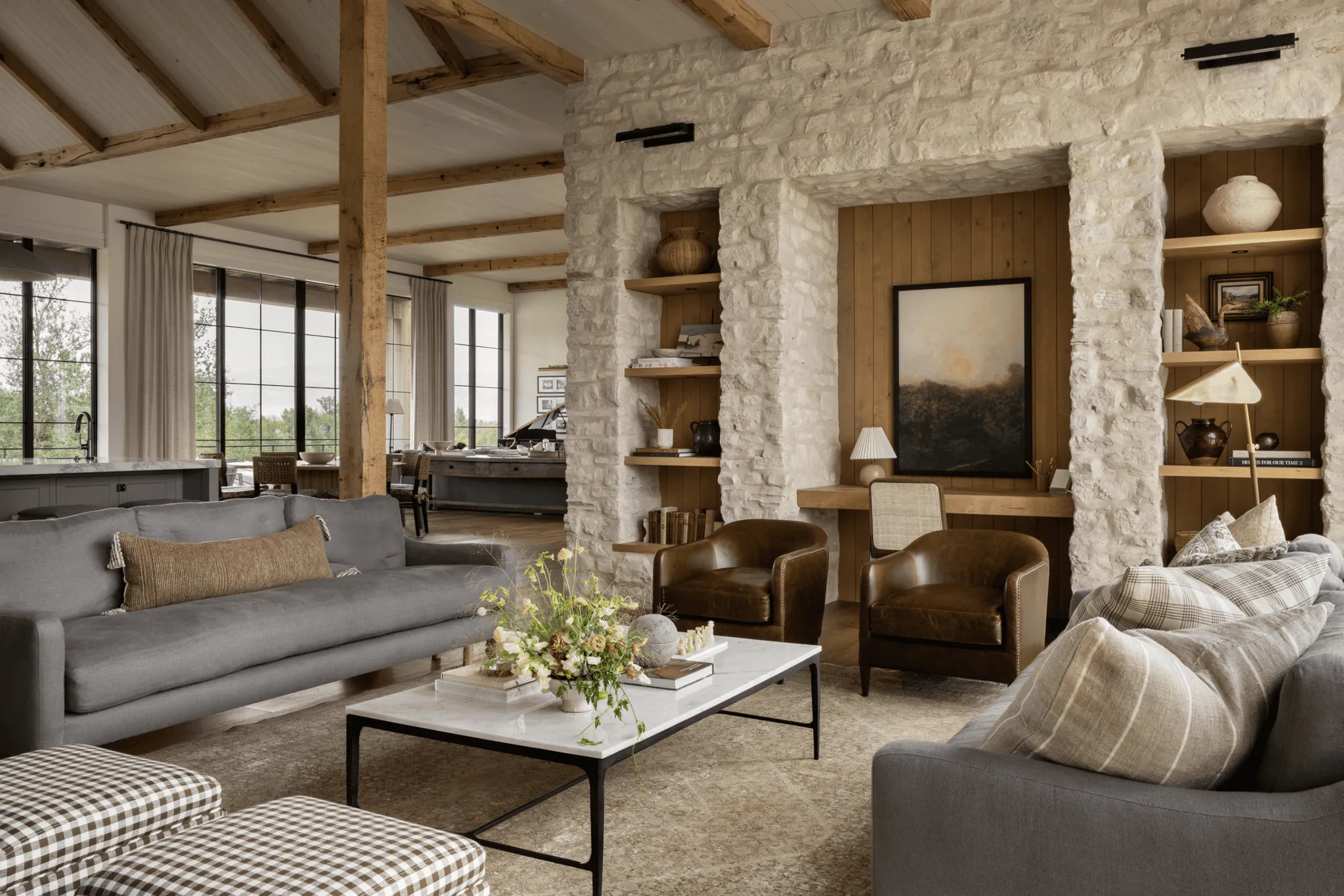 Finished hearth room with stone shelving, exposed beams, gray sofas, and leather chairs.