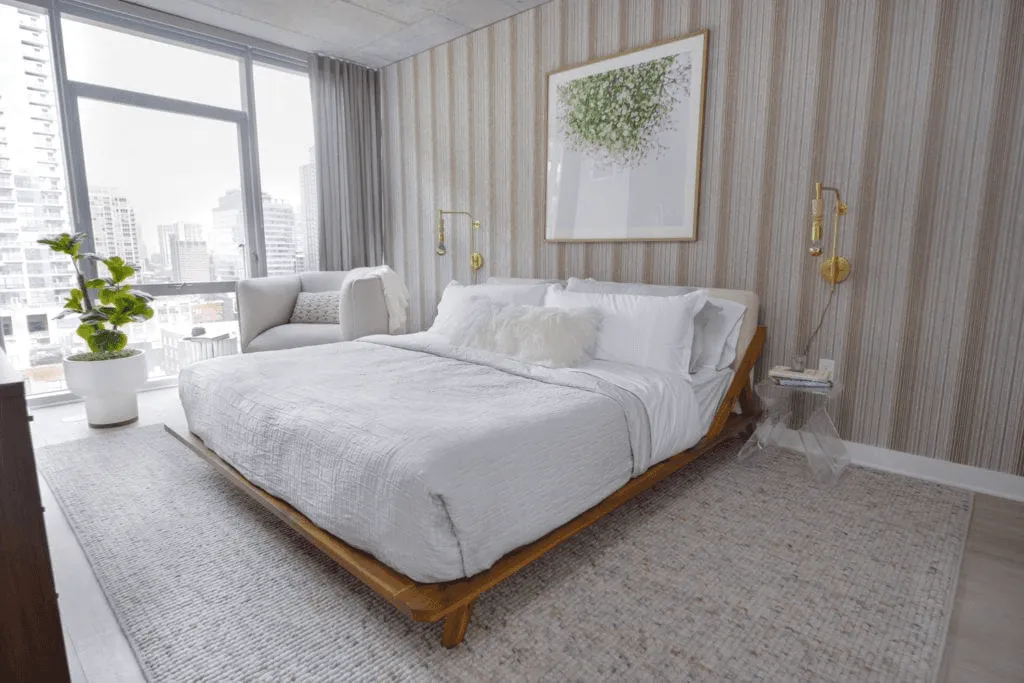 Finished bedroom with a wood platform bed, striped wall covering, and city views.