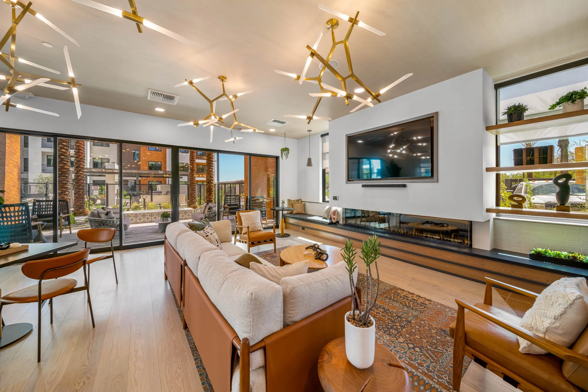 Bright lounge with sofas, leather chairs, a linear fireplace, and sculptural ceiling lights.